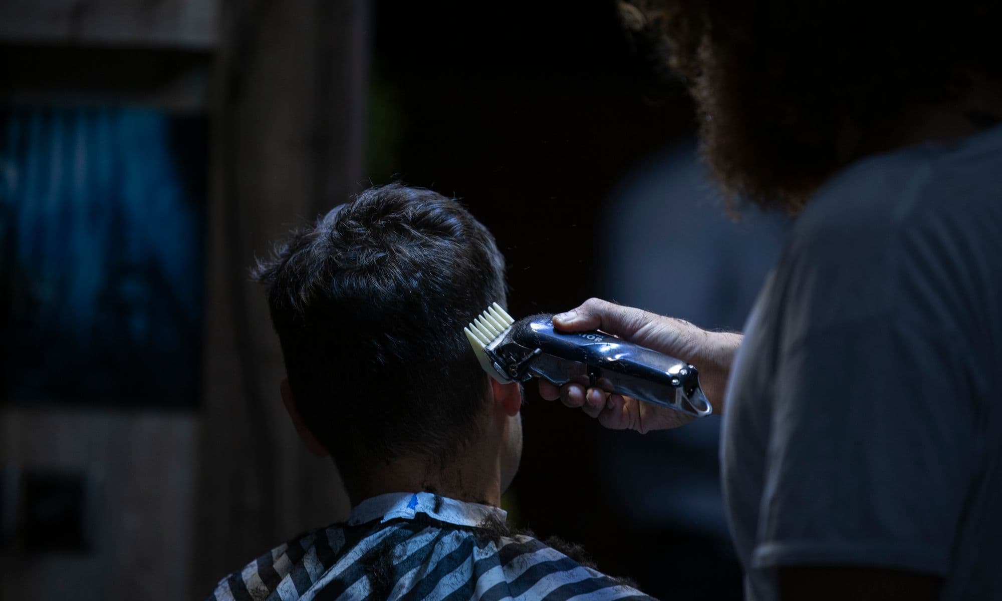 Barber aan het werk in een donkere barbershop